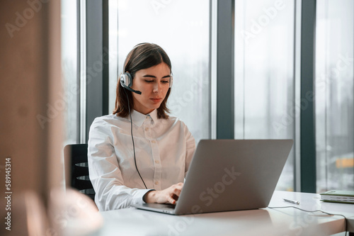 Beautiful young woman is working in the office by laptop