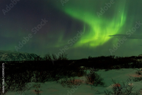 imagen de un paisaje nocturno nevado  con una aurora boreal en el cielo nocturno de Islandia 