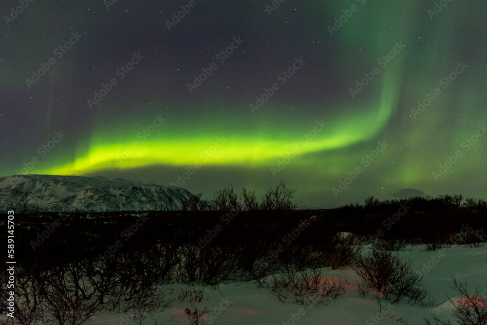 imagen de un paisaje nocturno nevado, con montañas de fondo, y una aurora boreal sobre el cielo de Islandia imagen de un paisaje nocturno nevado, con montañas de fondo, y una aurora boreal sobre el cielo de Islandia