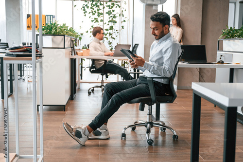Slika na platnu Talking behind the person that is sitting on the chair with digital device