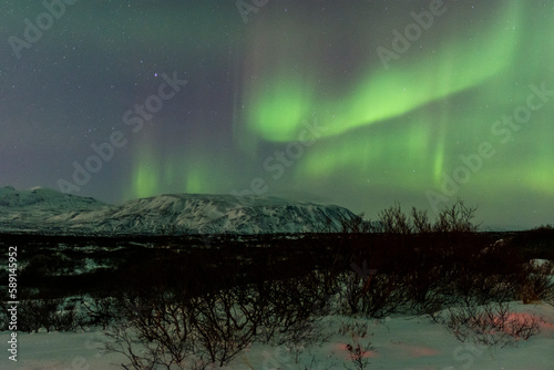 imagen paisaje nocturno con monta  as al fondo y una aurora boreal en el cielo estrellado de Islandia 