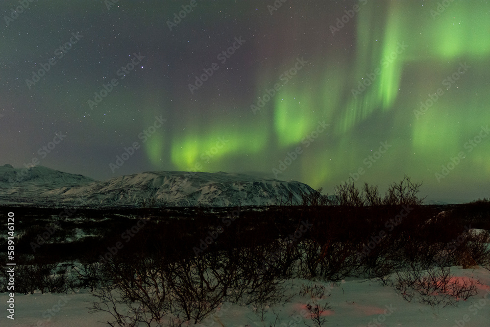 imagen nocturna de un paisaje nevado con una aurora boreal en el cielo nocturno de Islandia