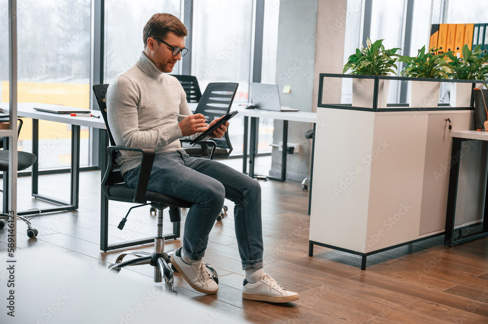 Office worker is sitting on the chair in the and using tablet Office worker is sitting on the chair in the and using tablet