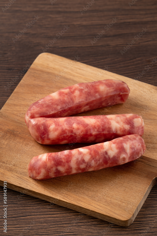 Raw Taiwanese sausage in garlic flavor in a plate on wooden table background. Raw Taiwanese sausage in garlic flavor in a plate on wooden table background.
