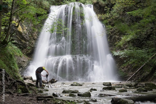 Rushing waterfall in the forest with a photographer capturing the view