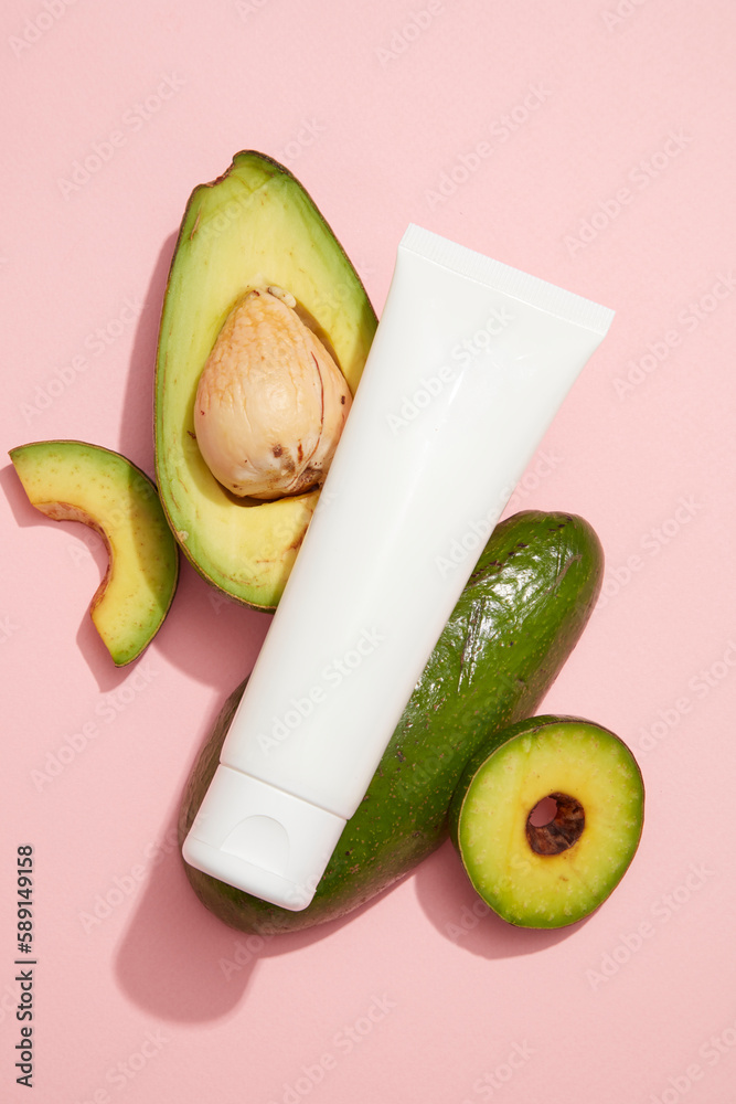 A white tube placed on Avocado slices. Blank label for beauty products ...
