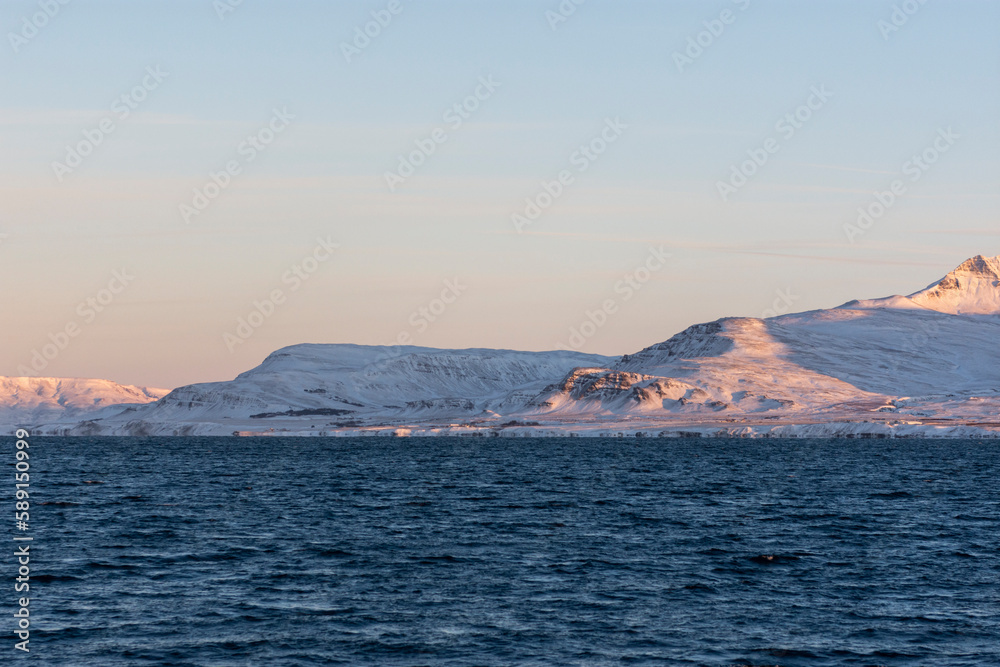 imagen de un paisaje con montañas nevadas, el cielo azul despejado y el mar