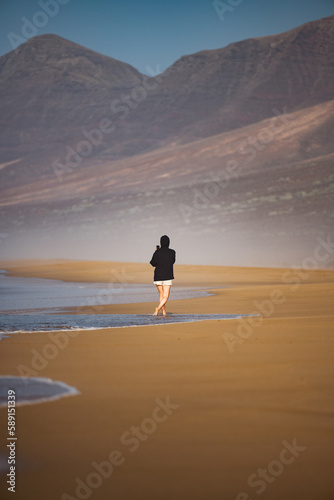 Obraz na płótnie Stunning view a person walking on the Cofete beach surrounded by the chain of mountains of the Jandía Natural Park. Fuerteventura, Canary Islands. w salonie