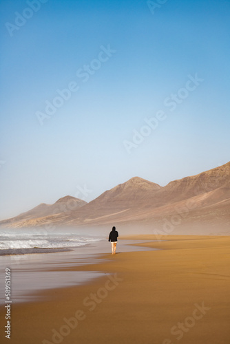 Obraz na płótnie Stunning view a person walking on the Cofete beach surrounded by the chain of mountains of the Jandía Natural Park. Fuerteventura, Canary Islands. w salonie