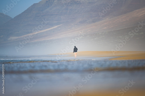 Obraz na płótnie Stunning view a person walking on the Cofete beach surrounded by the chain of mountains of the Jandía Natural Park. Fuerteventura, Canary Islands. w salonie