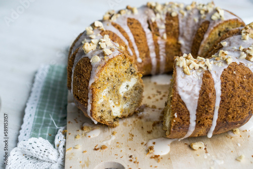 Carrot Bundt Cake with cheesecake swirl filling, white glaze on top with chopped nuts on white background cose up selective focus