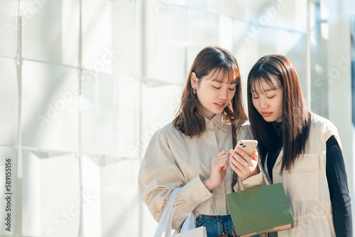 Tapety artystyczne スマホを見ながらショッピングをする友達同士の若い日本人女性
