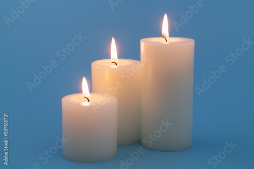 Scented candles burning on blue background close-up.	