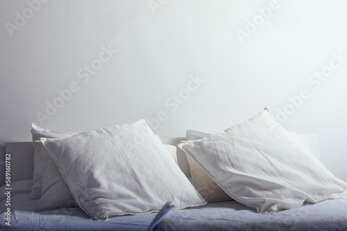 a bed with white linens in the rays of the sun