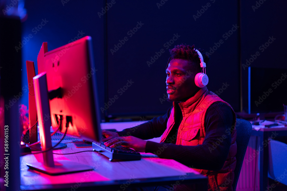 Young African man playing video game on computer. Streamer guy sitting at home and plays another match. Young African man playing video game on computer. Streamer guy sitting at home and plays another match.