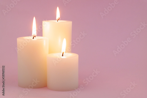 Three different white candled melting on pink background. Copy space for text.