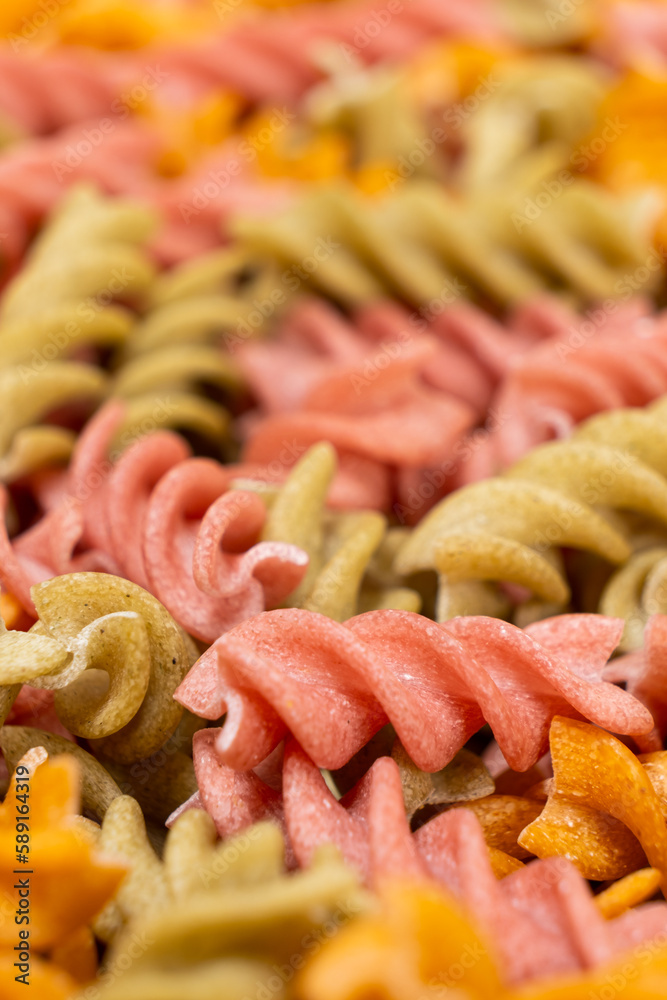 Rice vegetable pasta in the form of spirals, top view. Healthy rice pasta with tomatoes, selenera, carrots and beets Rice vegetable pasta in the form of spirals, top view. Healthy rice pasta with tomatoes, selenera, carrots and beets