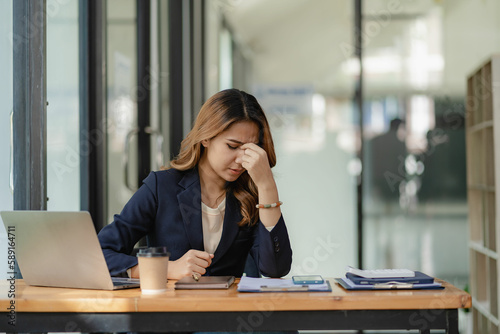 Konstfotografi Stressed and frustrated asian female accountant sitting at desk making serious b