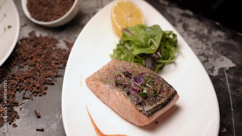 Grilled fish on plates with lettuce and vegetables with lemon on a table in an expensive restaurant Grilled fish on plates with lettuce and vegetables with lemon on a table in an expensive restaurant