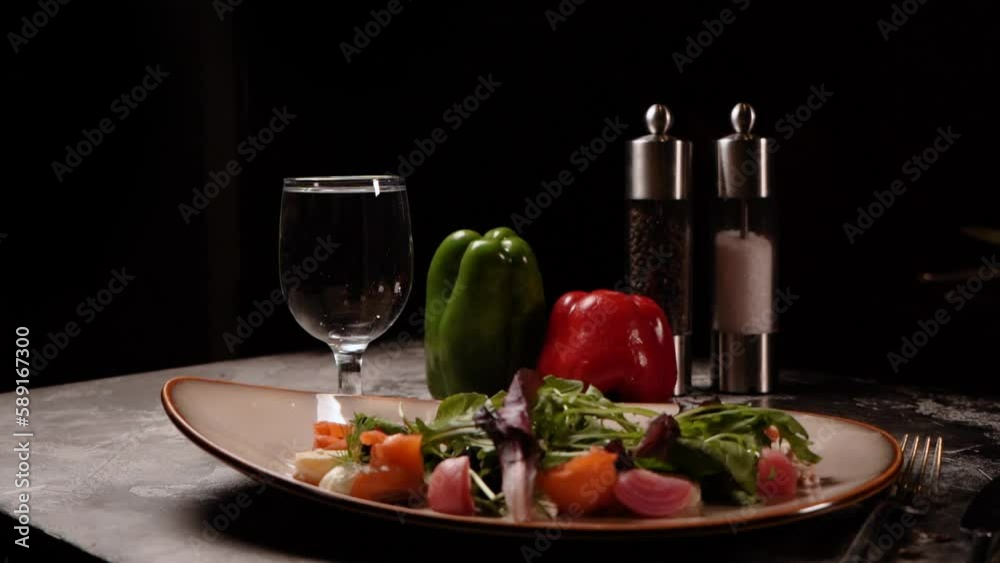 Fresh vegetables with seasonings and spices lie on the table and a salad with cheese vegetables tomatoes on a plate with forks in the dark in an expensive restaurant Fresh vegetables with seasonings and spices lie on the table and a salad with cheese vegetables tomatoes on a plate with forks in the dark in an expensive restaurant