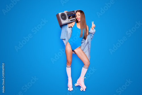 Party mood Full-size portrait of beautiful brunette girl on roller skates with a boombox showing v-sign and laughing isolated on bright pink background