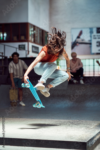 Young woman doing skateboard stunt at skateboard park