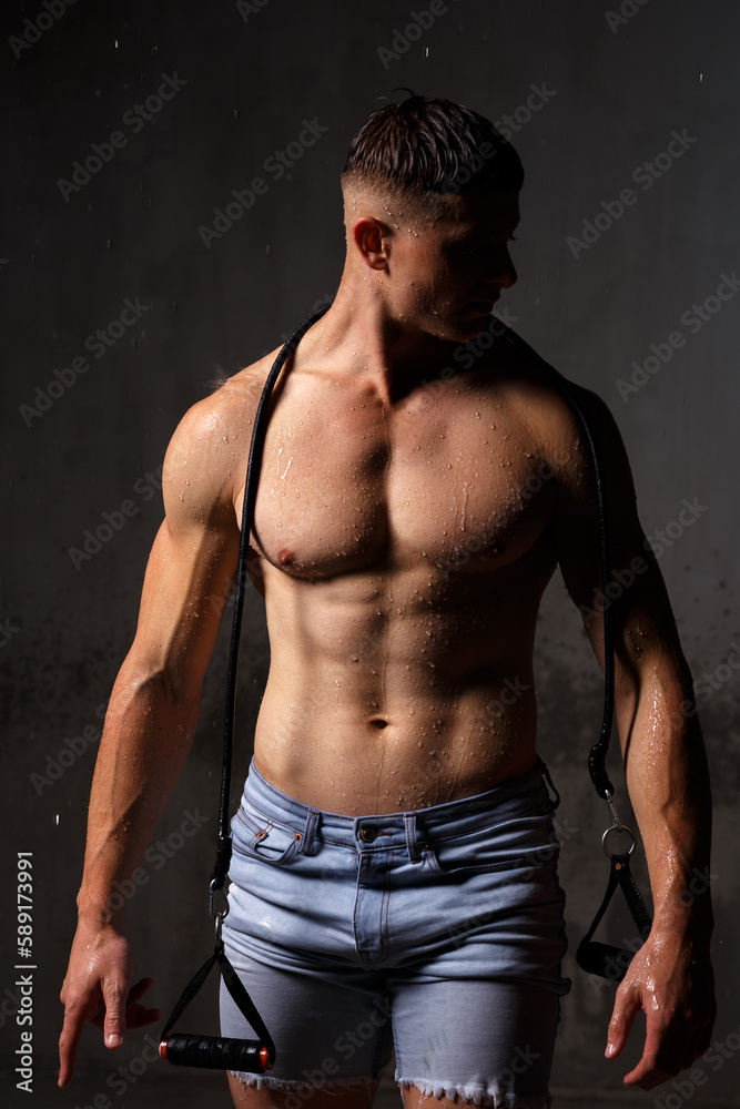 Fototapeta premium Athlete bodybuilder trains in the studio in the rain.