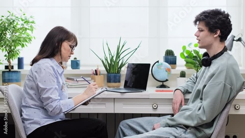 Confident serious female psychologist talking to young guy