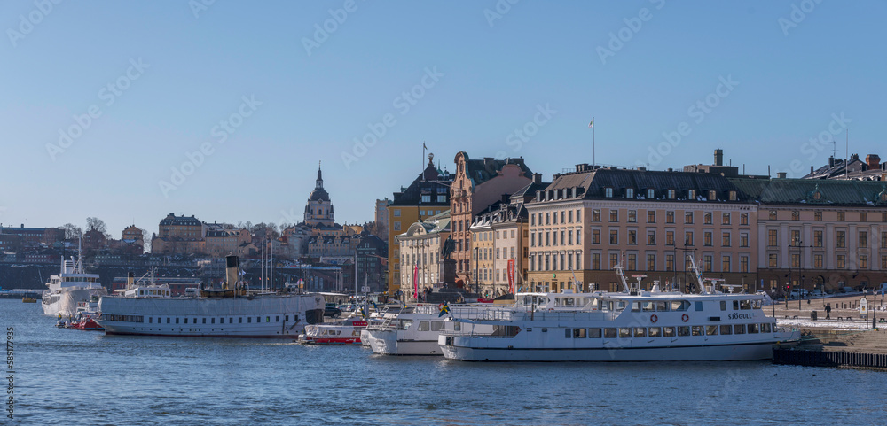 Steam and sightseeing boats in the bay Strömmen, the old own Gamla Stan, a sunny spring day in Stockholm