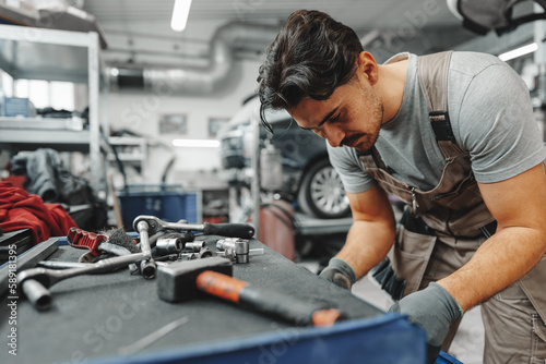 Male technician standing near tool table in car service