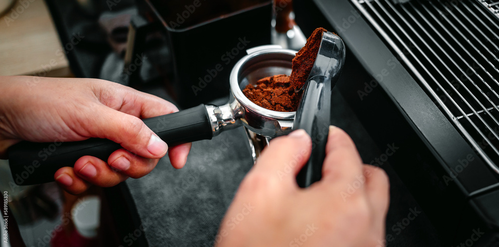 Coffeemaker's hand holding a spoon pouring coffee powder grinder grinding coffee pouring into a portafilter