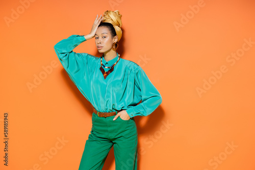 Young african american woman in summer outfit looking at camera on orange background.