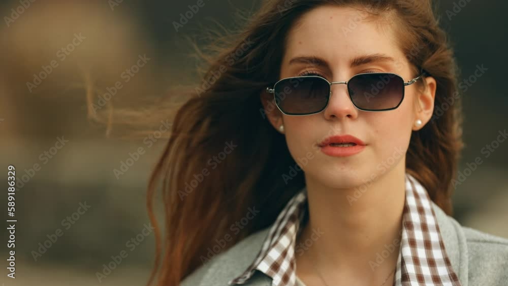Close-up portrait of a blue-eyed and long-haired beauty girl, the lady takes off her sunglasses and looks into the camera Close-up portrait of a blue-eyed and long-haired beauty girl, the lady takes off her sunglasses and looks into the camera