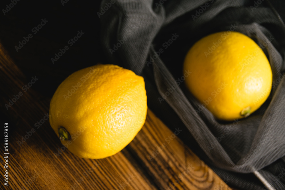 Flatlay, lemons on a cutting board and in a fruit net on a dark background. Earth day and zero waste concept