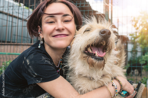 Dog at the shelter. Animal shelter volunteer feeding the dogs. Dogs in cage with cheerful woman volunteer photo