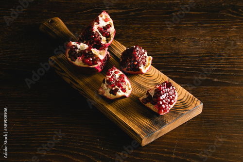 Pomegranate pieces on a cutting board on a dark background