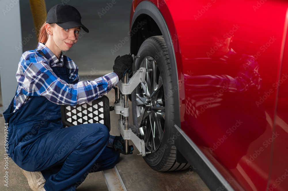 A female auto mechanic makes a camber. Woman working in a car service. A female auto mechanic makes a camber. Woman working in a car service.