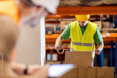 A warehouseman is packing box for export while standing in storage.