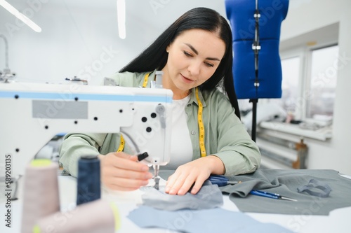 Young woman working as seamstress in clothing factory.