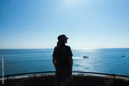 Nature scenic landscape female silhouette in hat against seascape in sunny day. Beautiful mediterranean sea in sunny summer day. Tourist on summer holiday vacation trip. High quality photo