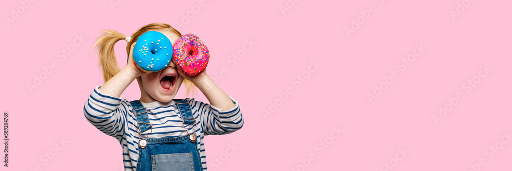 Happy cute girl is having fun played with donuts on black background wall. - obrazy, fototapety, plakaty 