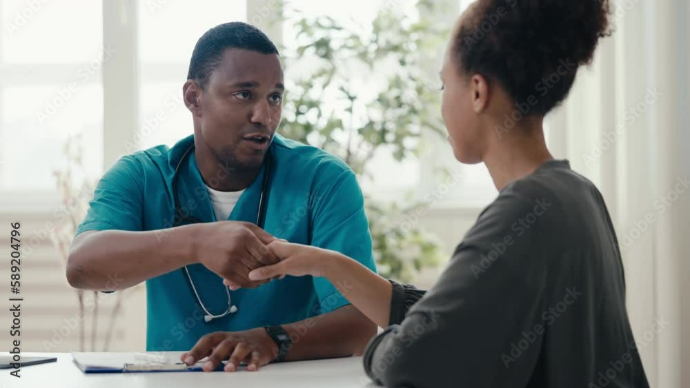 African American male doctor talking with happy female patient, shaking hands African American male doctor talking with happy female patient, shaking hands