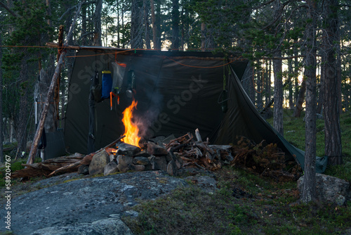Fototapeta Naklejka Na Ścianę i Meble -  A camp with a laavu shelter on a rock with a fire in front