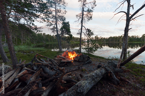 Fototapeta Naklejka Na Ścianę i Meble -  Campfire and firewood with lake Inarijärvi in Lapland, Finland in the background