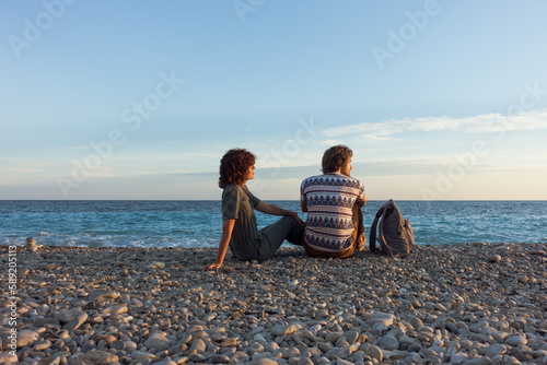 Beach summer couple on vacation. Holiday relax in the sunset with sea view at pebble beach, Idyllic travel background. High quality photo
