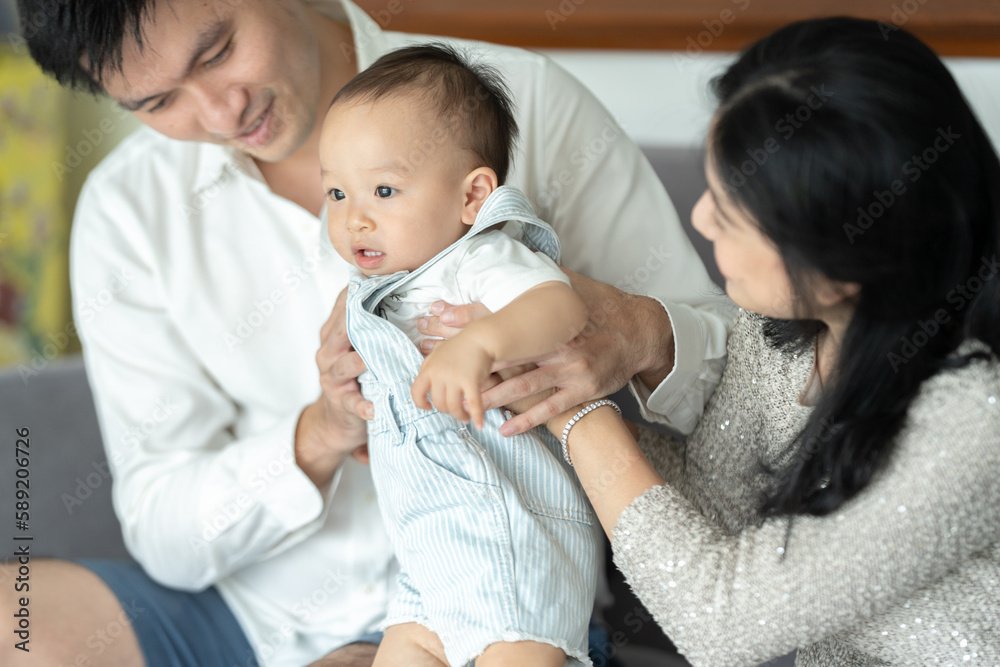 Father's Day concept, young Asian father holding a baby child with family person at home, happy childhood with love and care together, little cute son with dad and parent, parenthood lifestyle Father's Day concept, young Asian father holding a baby child with family person at home, happy childhood with love and care together, little cute son with dad and parent, parenthood lifestyle