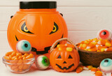Halloween candy corn,jelly eye, pumpkin candy, sugar skull in different bowls on white background.Classic candy sweets for Halloween with.Halloween holiday concept with candy corn and jack o lantern.