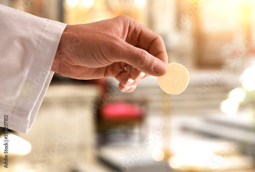 Hand of a priest giving a consecrated host for communion