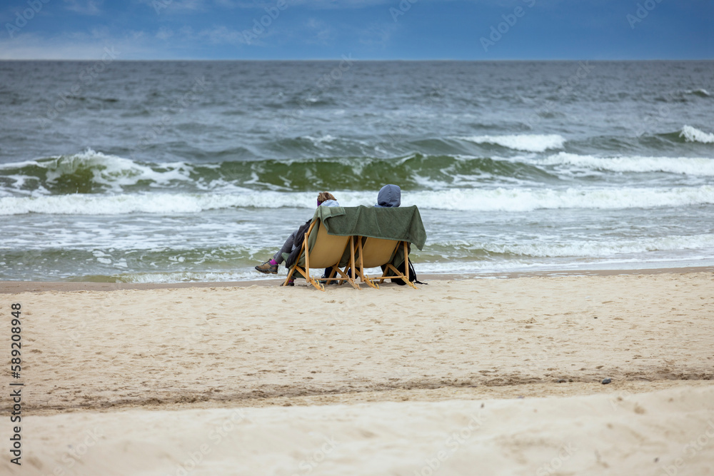 Φωτογραφία Two people are sitting on deckchairs on the sand of the Baltic Sea, iodine inhal