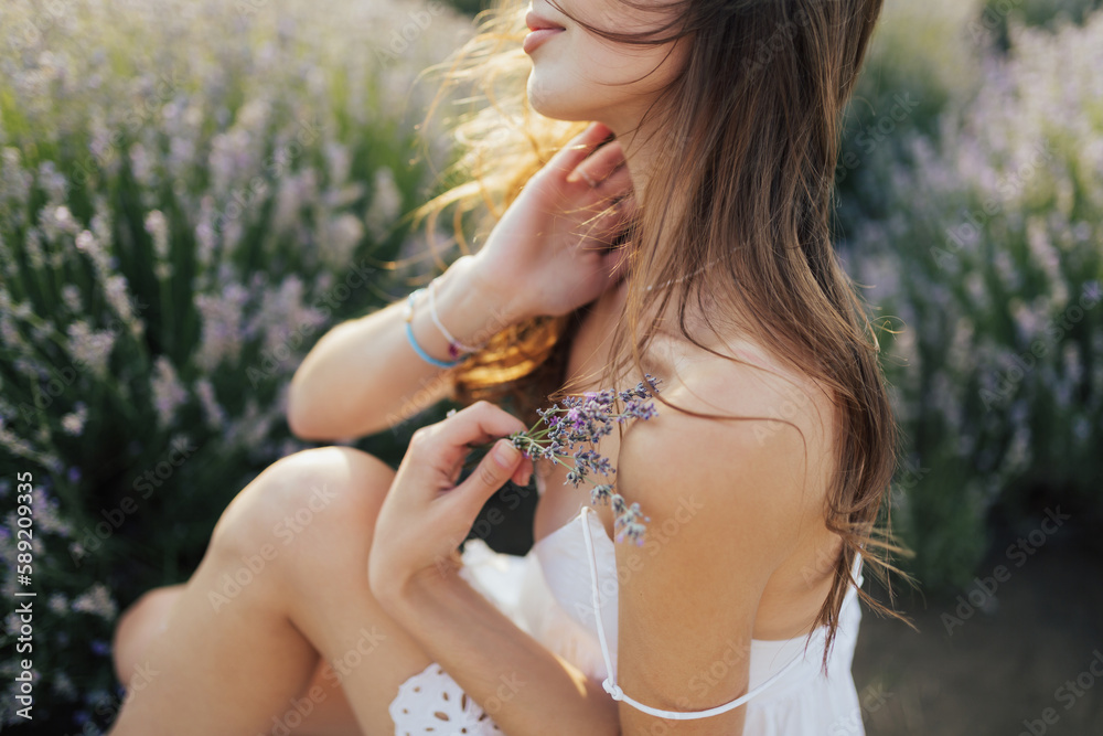 Cropped shot of relaxed woman holding a small bouquet of lavender and enjoying free moment at summer picnic.
